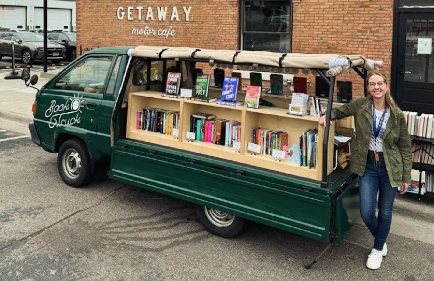 Rachel Cleveland is depicted next to her green Little Charity Book Truck.