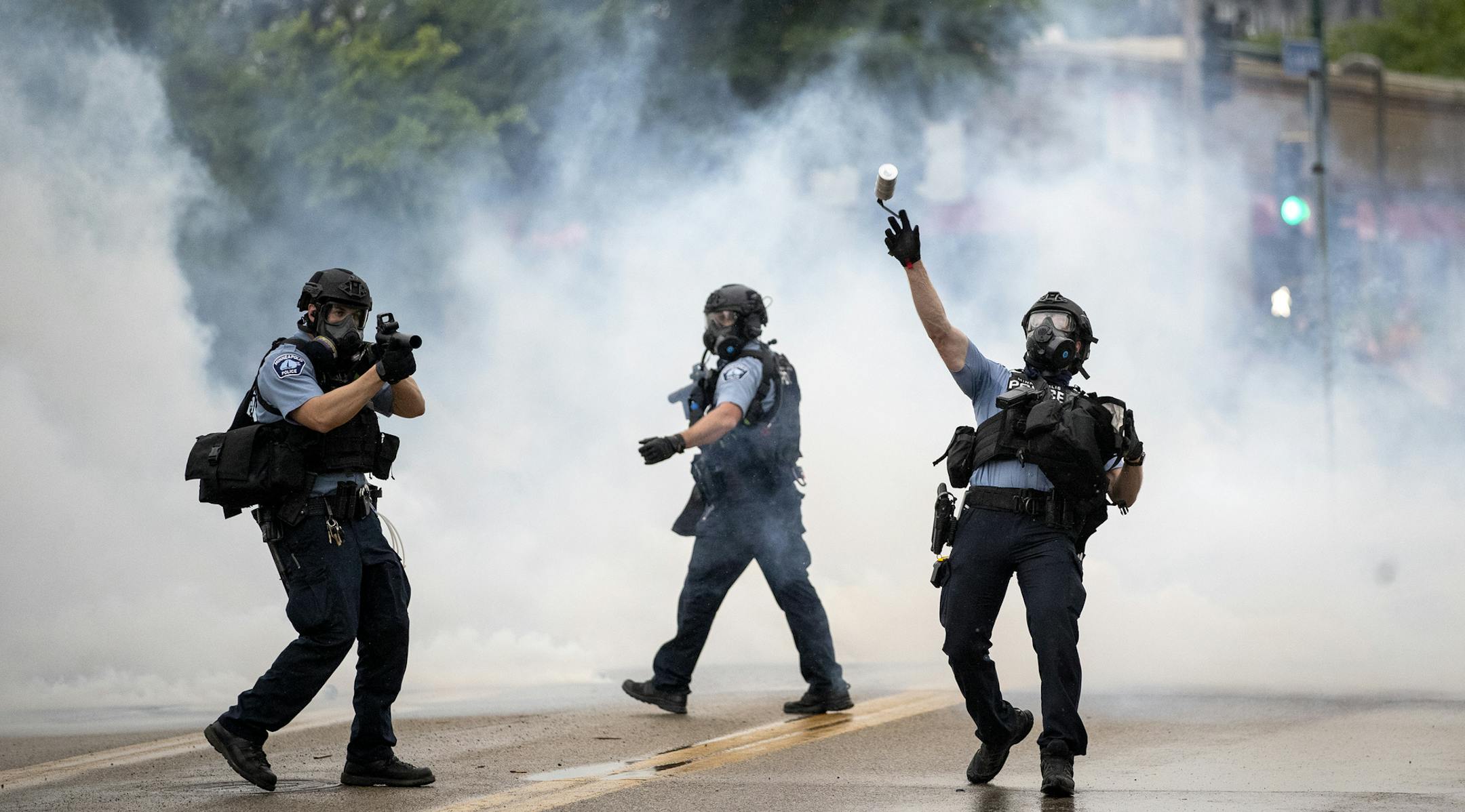 A police officer throws a tear gas canister towards protesters at the Minneapolis 3rd Police Precinct, following a rally for George Floyd on Tuesday, May 26, 2020, in Minneapolis. Four Minneapolis officers involved in the arrest of Floyd, a black man who died in police custody, were fired Tuesday, hours after a bystander's video showed an officer kneeling on the handcuffed man's neck, even after he pleaded that he could not breathe and stopped moving. (Richard Tsong-Taatarii/Star Tribune via AP)