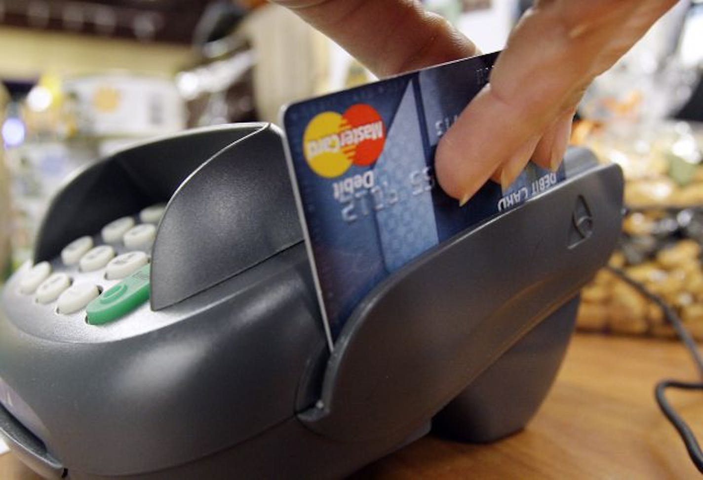 FILE - In this Nov. 2, 2009 file photo, a customer swipes a MasterCard debit card through a machine while checking-out at a shop in Seattle. Bankers and merchants, pillars of the business world and frequent allies, are engaged Thursday, March 10, 2011,in a bitter lobbying war over something Americans do 38 billion times a year _ swipe a debit card.