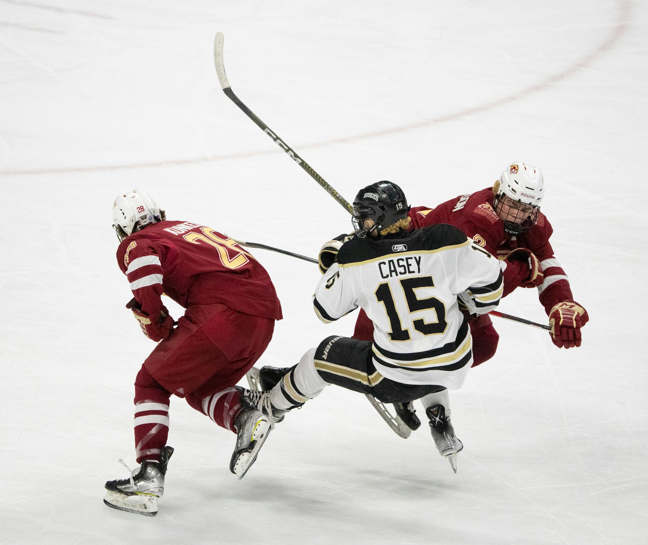 Lakeville South Cougars defenseman Ryder Patterson (2) checked Andover Huskies forward Cayden Casey (15) off the puck, allowing teammate defenseman Colton Kunkel (28) to skate away with it in the first period.