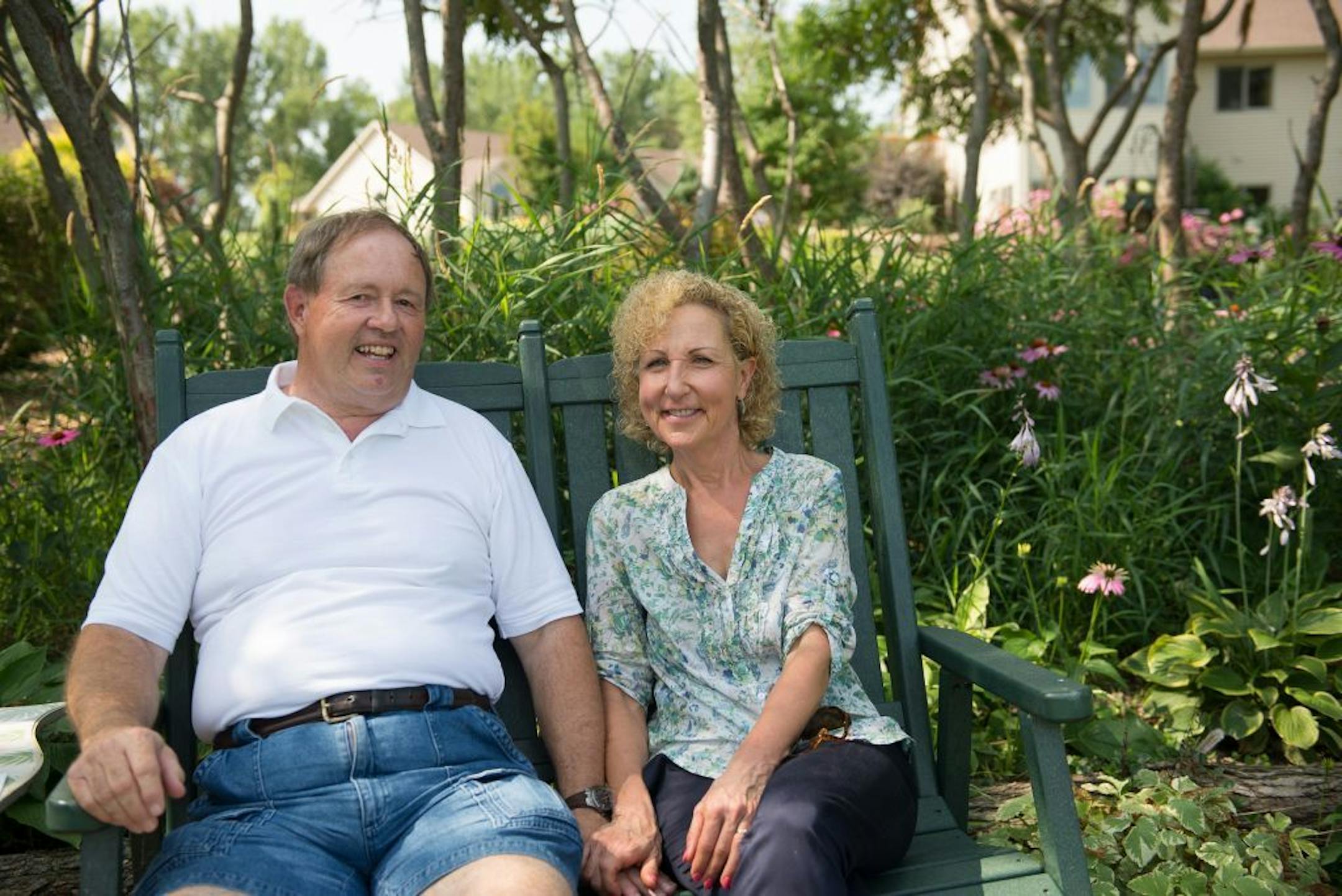 Dan and Nancy Engebretson sit on a bench with a view out over Tustin Lake in the common area that they garden next to their home, seen in rear at right, in Elysian, Minnesota on July 31, 2014. [ Angela Jimenez/Special to the Star-Tribune angelajime@gmail.com Assignment #20035606A_ SLUG: ENGEBRETSON100114_ EXTRA INFORMATION: Since 2006, the Engebretsons have designed and tended to their own garden, and have transformed the common space near their home into a landscaped, shared garden space in the