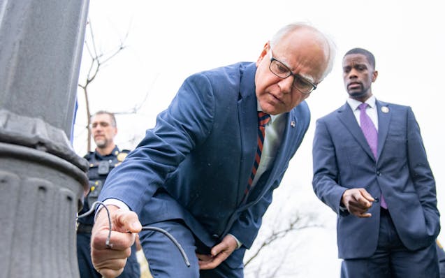 Minnesota Governor Tim Walz and St. Paul Mayor Melvin Carter inspect one of many lamp posts that have been illegally stripped for copper wire at Como 