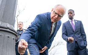 Minnesota Gov. Tim Walz and St. Paul Mayor Melvin Carter inspect one of many lamp posts that have been illegally stripped for copper wire at Como Lake