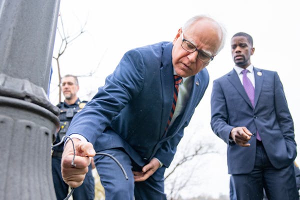Minnesota Gov. Tim Walz and St. Paul Mayor Melvin Carter inspect one of many lamp posts that have been illegally stripped for copper wire at Como Lake