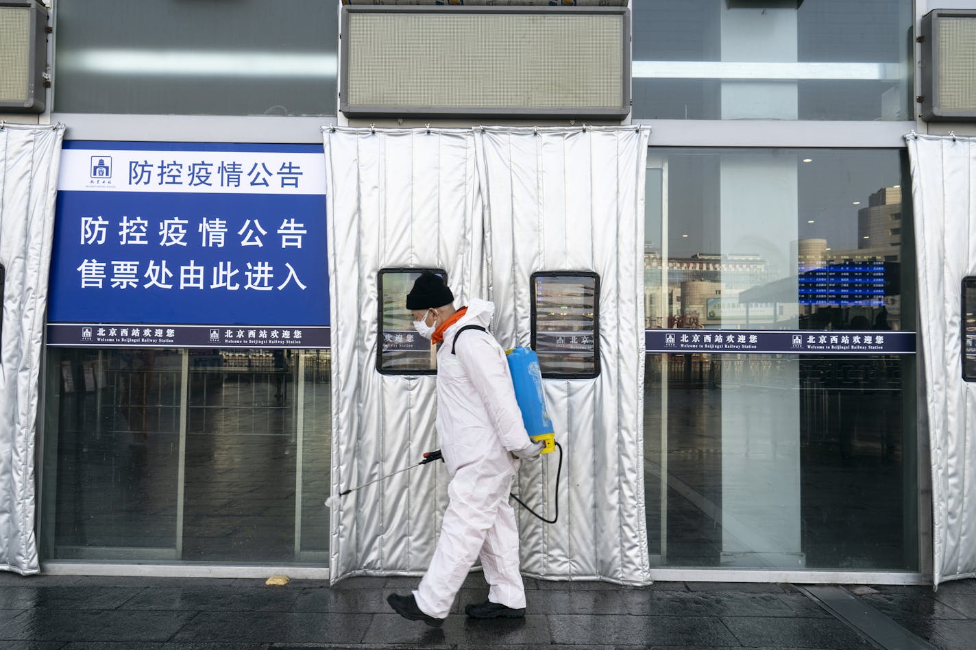 A worker sprays disinfectant at the entrance of Beijing West railway station in an effort to protect against the coronavirus earlier this month. (Giulia Marchi/The New York Times)