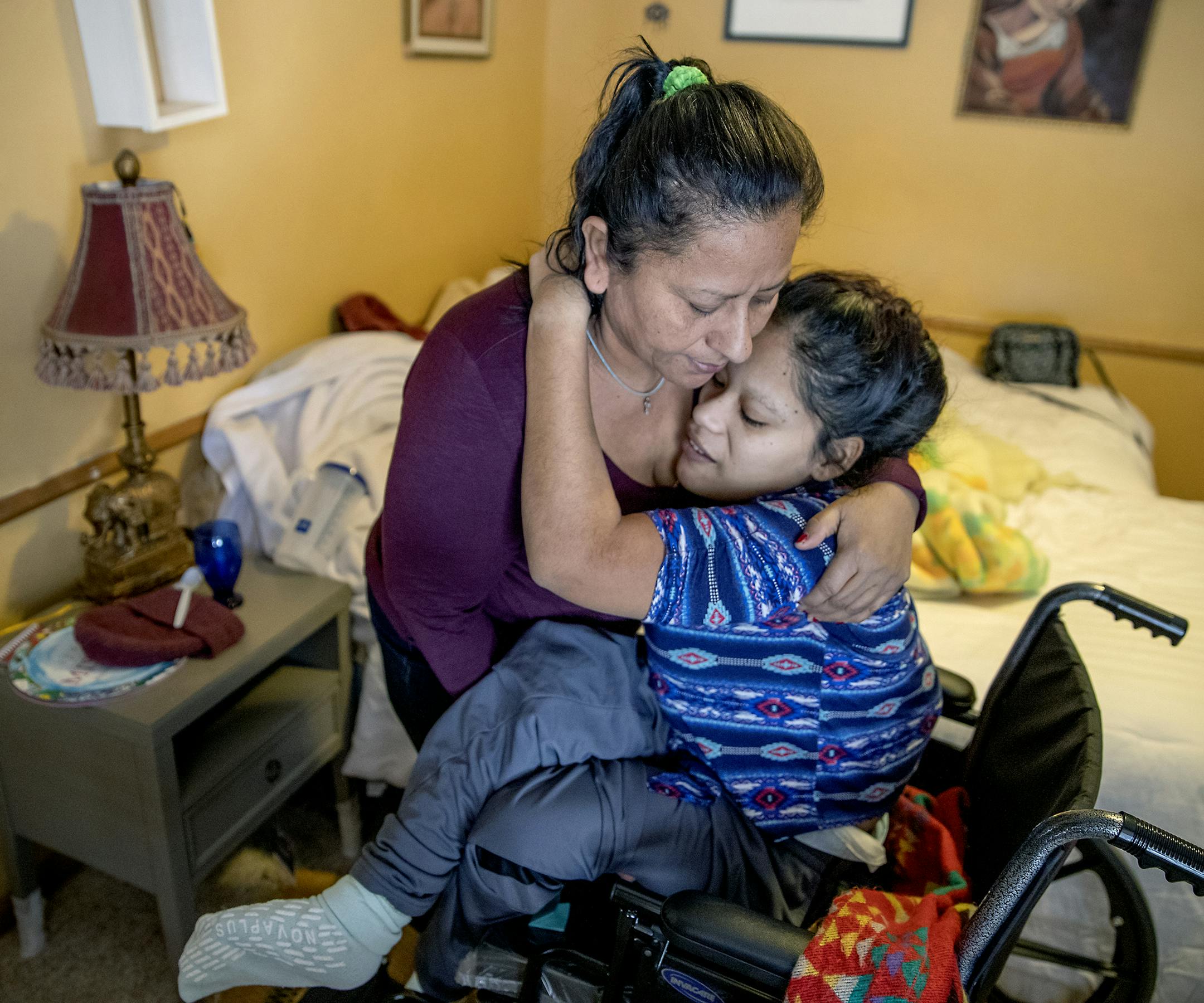 Maria Madalena Carranza placed her daughter Sarai in her wheelchair to make her way to lunch at a home where they took refuge after an emergency visit to HCMC, Friday, February 1, 2019 in Golden Valley, MN. Maria and her daughter Sarai and other members of her family fled gang intimidation in El Salvador and made it to Minnesota with a caravan last summer. ] ELIZABETH FLORES &#x2022; liz.flores@startribune.com