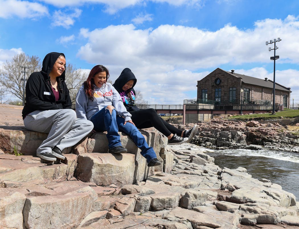 Bonna BigCrow, Kara Ashley and Brianna Roan Eagle laugh together while sitting on the rocks at Falls Park in Sioux Falls. (Erin Bormett / Argus Leader)