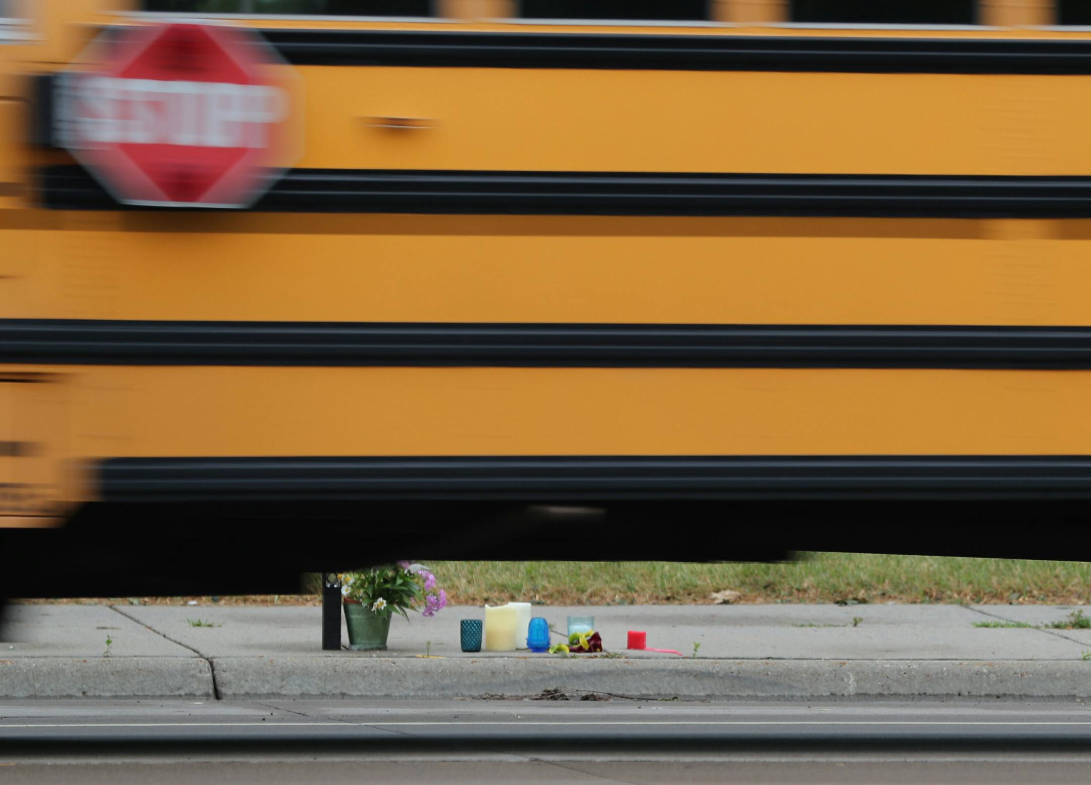 A school bus rolls by a memorial on the Larpenteur Ave. W. sidewalk in Falcon Heights Thursday, July, 7, 2016, near where Philando Castile, 32, a St. Paul schools employee, was shot by a police officer and later died Wednesday night at HCMC. The shooting followed a traffic stop in Falcon Heights, MN.