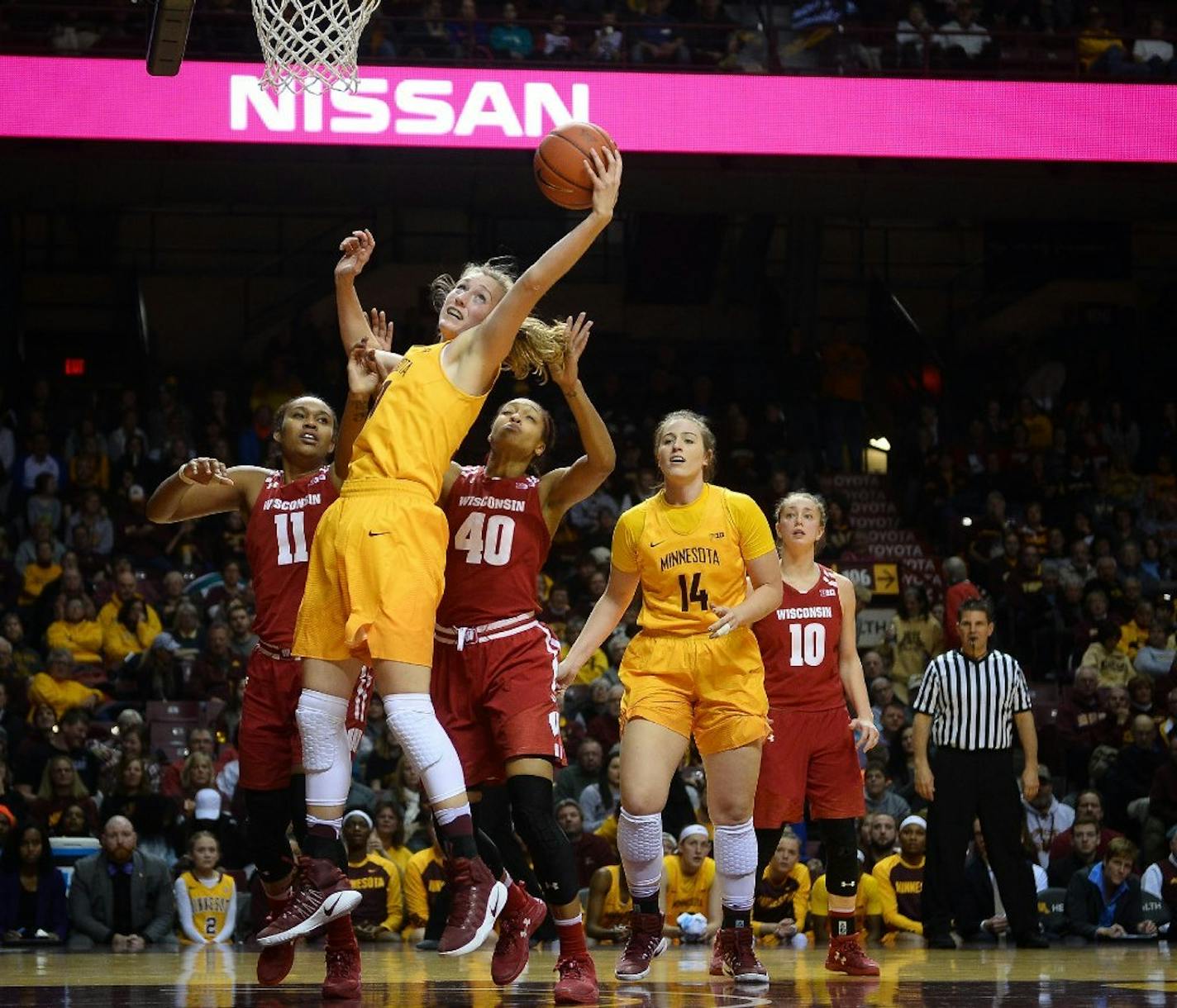 Gophers forward Whitney Tinjum (30) made a rebound between Wisconsin Badgers forward/center Marsha Howard (11) and forward Avyanna Young