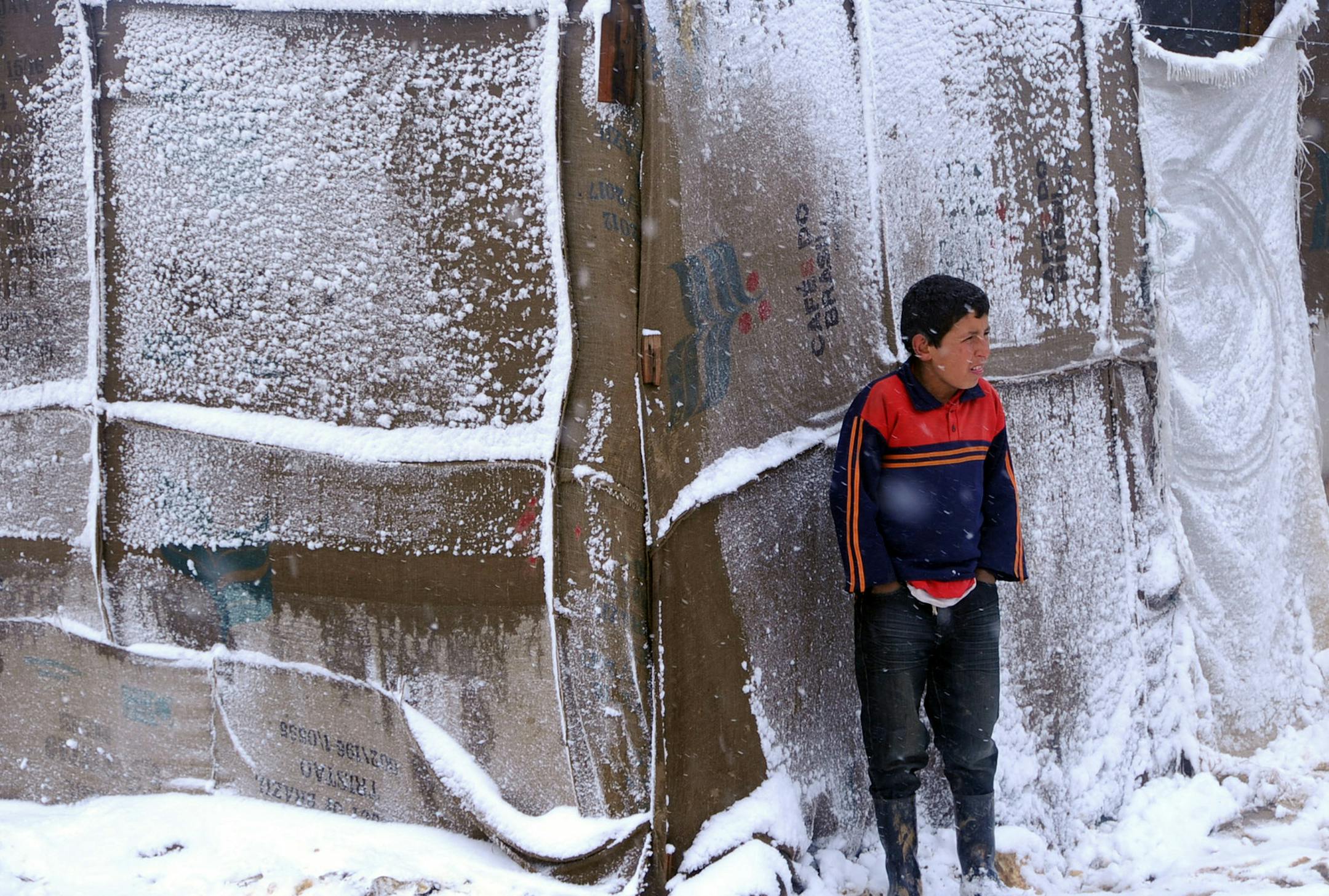 A Syrian refugee boy stands outside his tent as a heavy snowstorm batters the region, in a camp for Syrians who fled their countryís civil war, in the Bekaa valley, eastern Lebanon, Wednesday, Dec. 11, 2013. The United Nations refugee agency says it is "extremely concerned" for hundreds of thousands of Syrian refugees scattered across the region amid a snowstorm with high winds and torrential rains. (AP Photo)