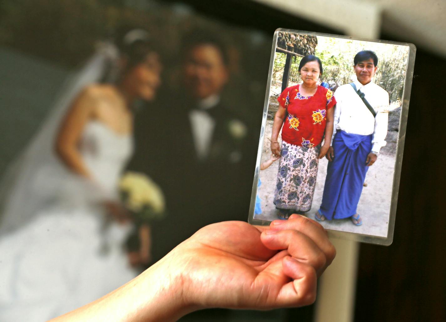 Ximenes Zedekiah held a photograph of his wife parents Ma Khin left (mother) and Aung Myint (father) in front of his wedding portrait with his wife Angela Paw Wednesday 13, 2012 in St. Paul, MN. They are trying to bring Angela's parents here from a refugee camp in Thailand so they can all be reunited as a family. Angela and her husband are both originally from Burma. ] JERRY HOLT &#x201a;&#xc4;&#xa2; jerry.holt@startribune.com