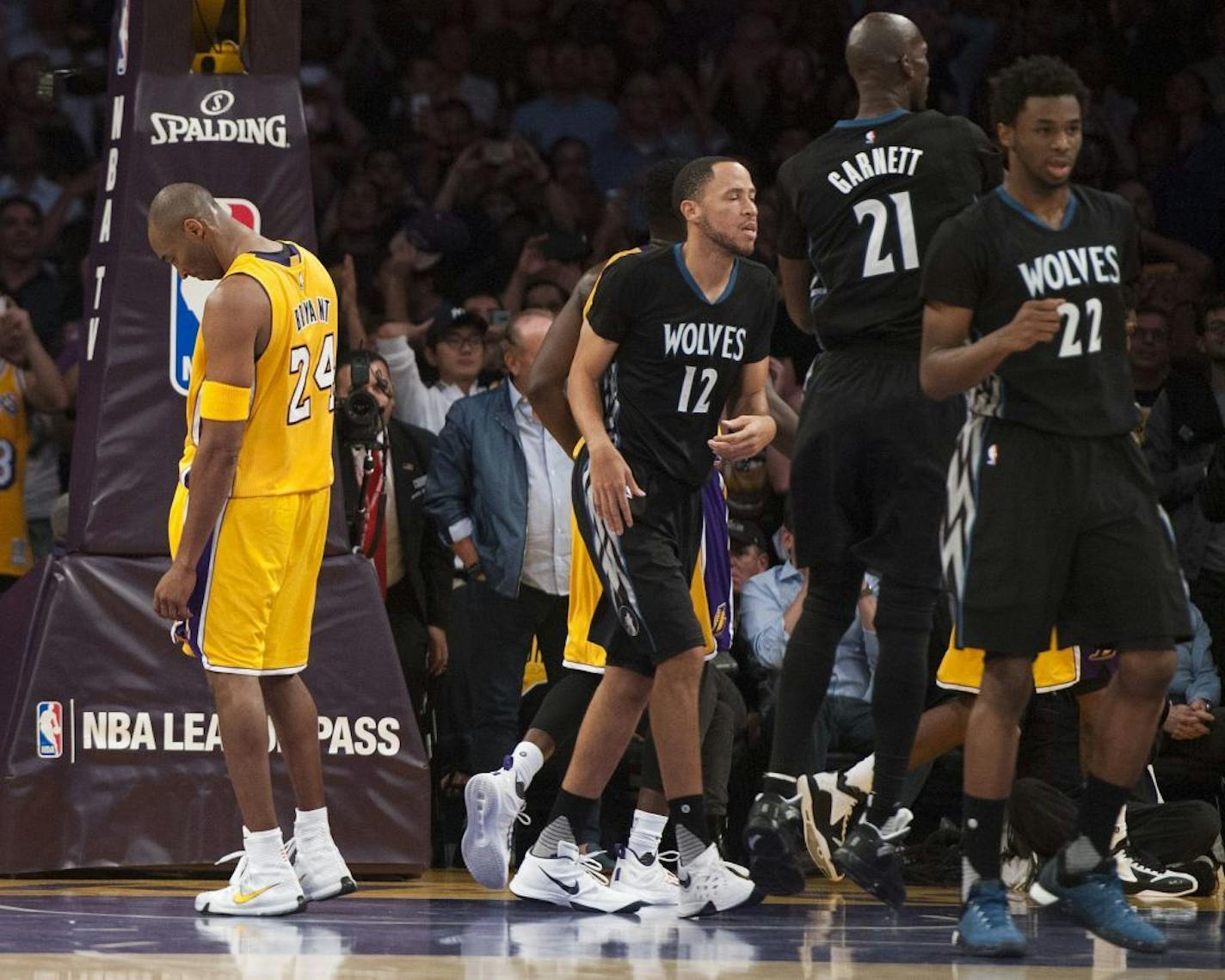 Los Angeles Lakers' Kobe Bryant hangs his head as the Minnesota Timberwolves celebrate their 112-111 victory in an NBA basketball game Wednesday, Oct. 28, 2015, in Los Angeles.