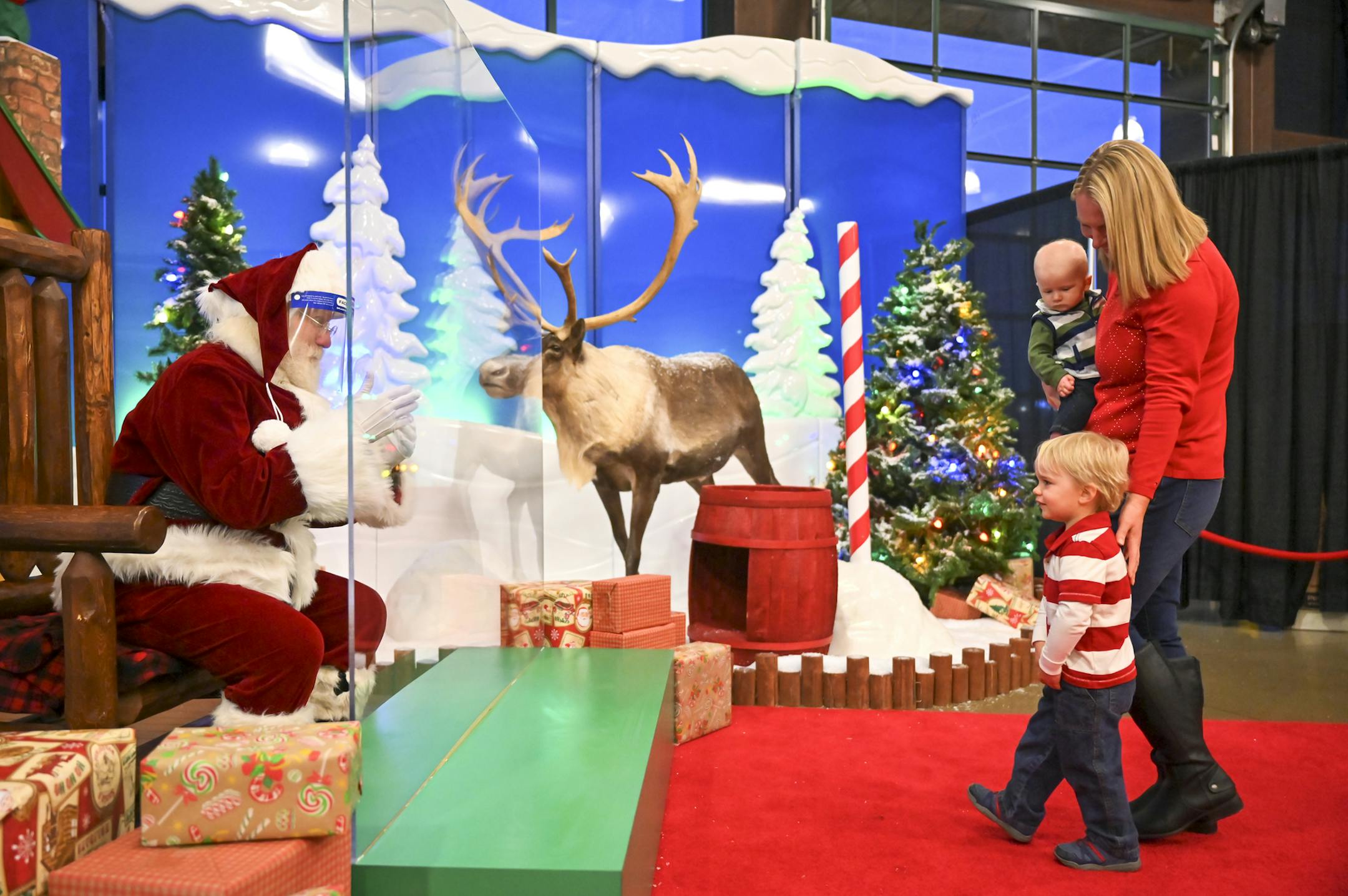 Shannon Mueller, of Husdon, Wis., walked up to "Santa Scott," with her bashful 2-year old, Porter, and 5-month old, Rylan, before taking photos Nov. 11 at the Cabela's in Woodbury. "It's a little different," Mueller said of the temperature checks, plexiglass barrier, and contact-free experience with Santa."But I think being with Santa never loses its magic for the kids."