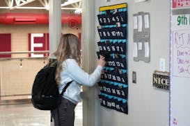 A ninth-grader places her cellphone into a phone holder on the way into class in Delta, Utah.
