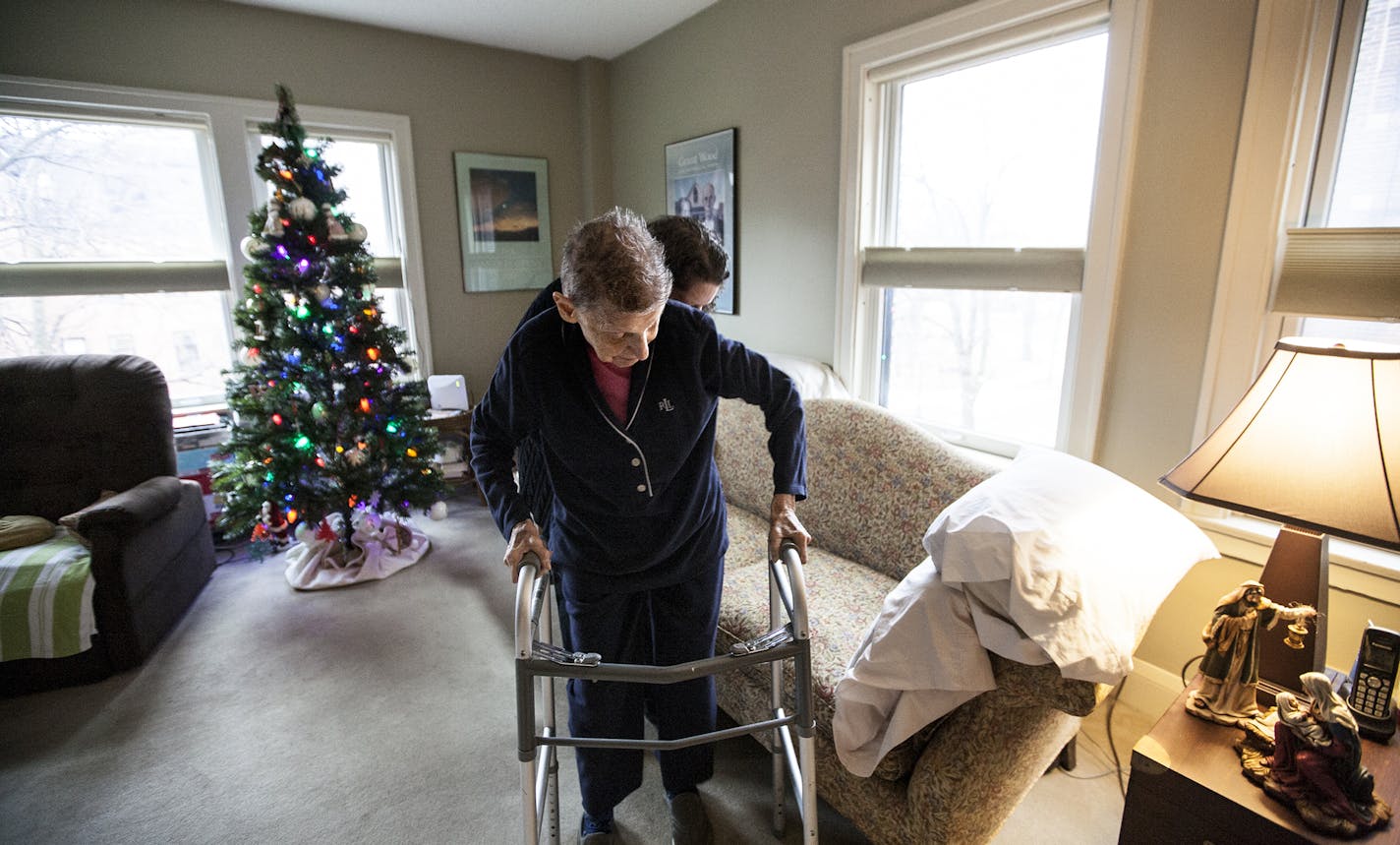 Sally Evans, behind, helps her mother Wilma Evans take a seat on a couch that has motion sensors underneath the cushions at their condominium in St. Paul December 15, 2015. (Courtney Perry/Special to the Star Tribune)