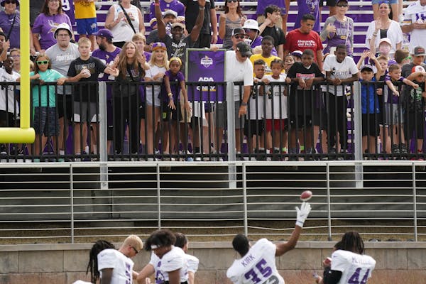 Vikings players throw mini footballs to fans after practice Wednesday. 