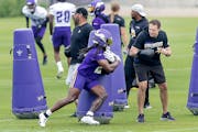Vikings Head Coach Kevin O'Connell, right, helps with drills and waits for running back Alexander Mattison to round the pads during practice at the TC