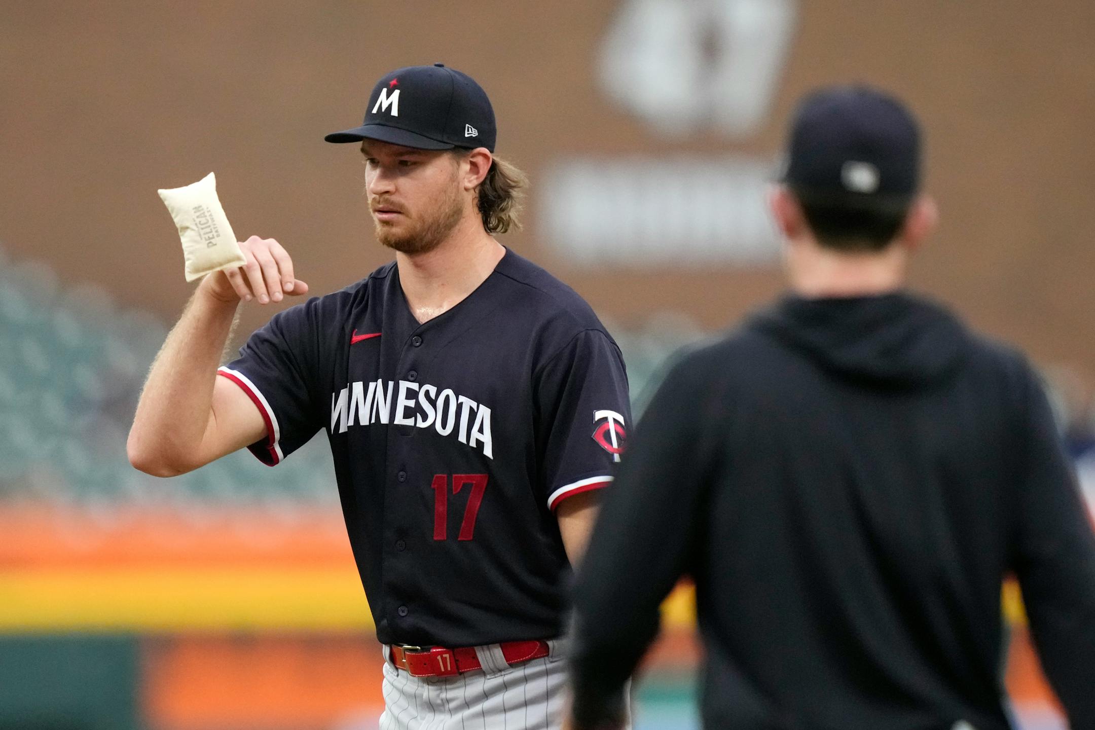 Minnesota Twins starting pitcher Bailey Ober tosses the rosin bag as pitching coach Pete Maki visits the mound during the third inning of a baseball game against the Detroit Tigers, Wednesday, Aug. 9, 2023, in Detroit. (AP Photo/Carlos Osorio)
