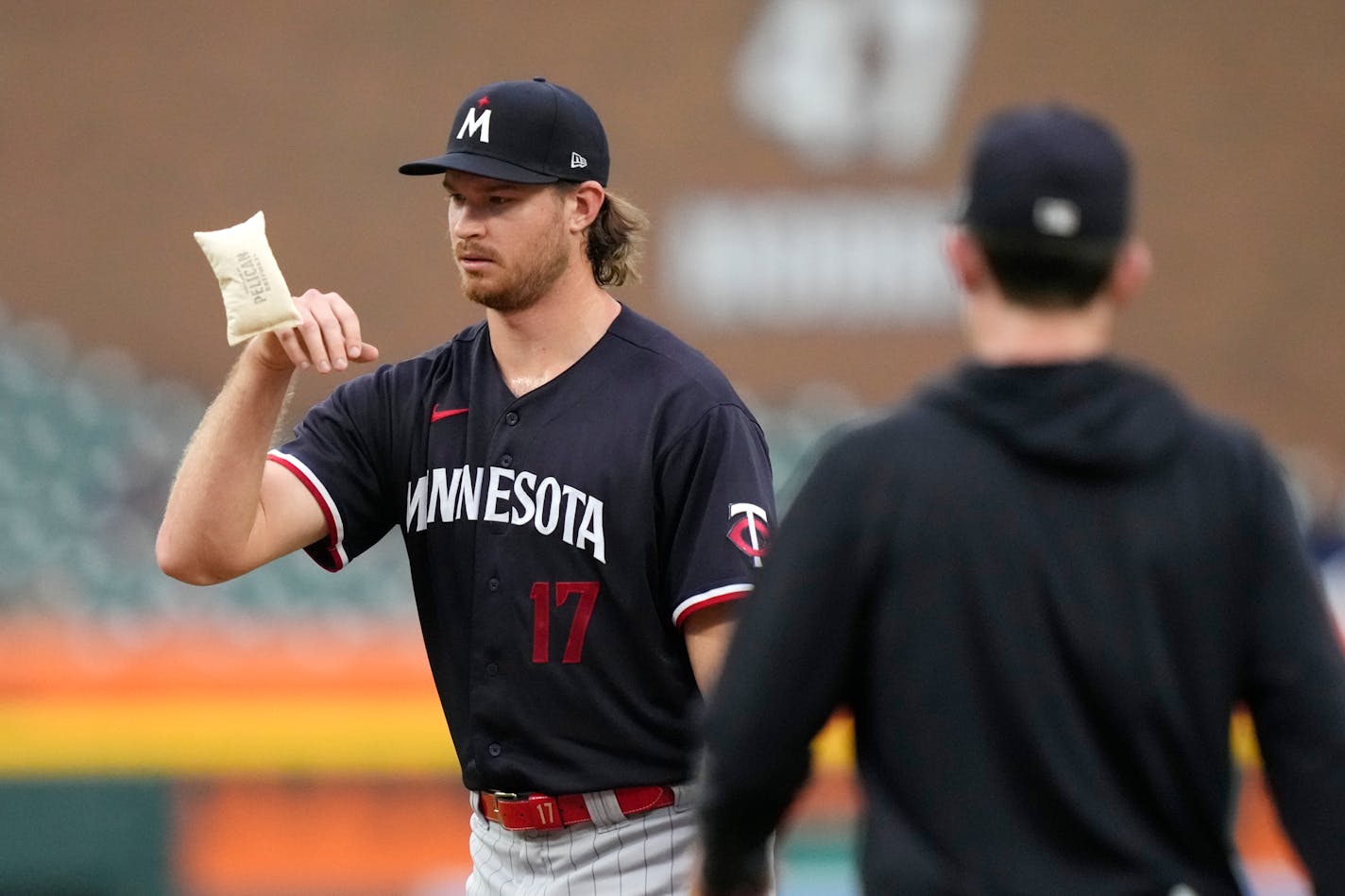 Minnesota Twins starting pitcher Bailey Ober tosses the rosin bag as pitching coach Pete Maki visits the mound during the third inning of a baseball game against the Detroit Tigers, Wednesday, Aug. 9, 2023, in Detroit. (AP Photo/Carlos Osorio)