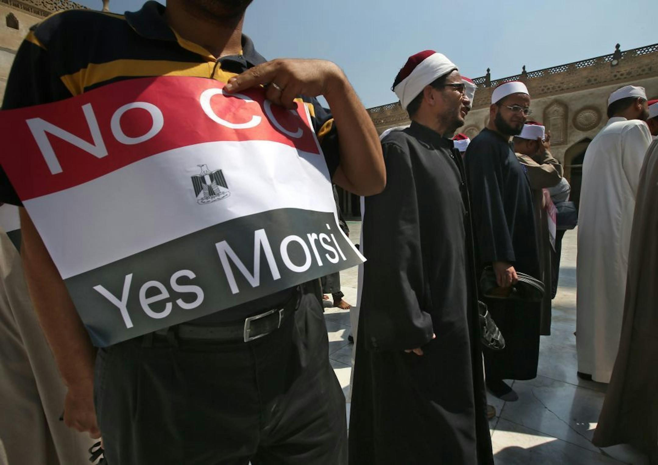 An Egyptian supporter of ousted Egyptian President Mohammed Morsi holds up a placard against Egyptian Defense Minister General Abdul Fatah al-Sisi as he leaves with clerics following a protest at al-Azhar mosque in Cairo, Egypt, Sunday, July 14, 2013.