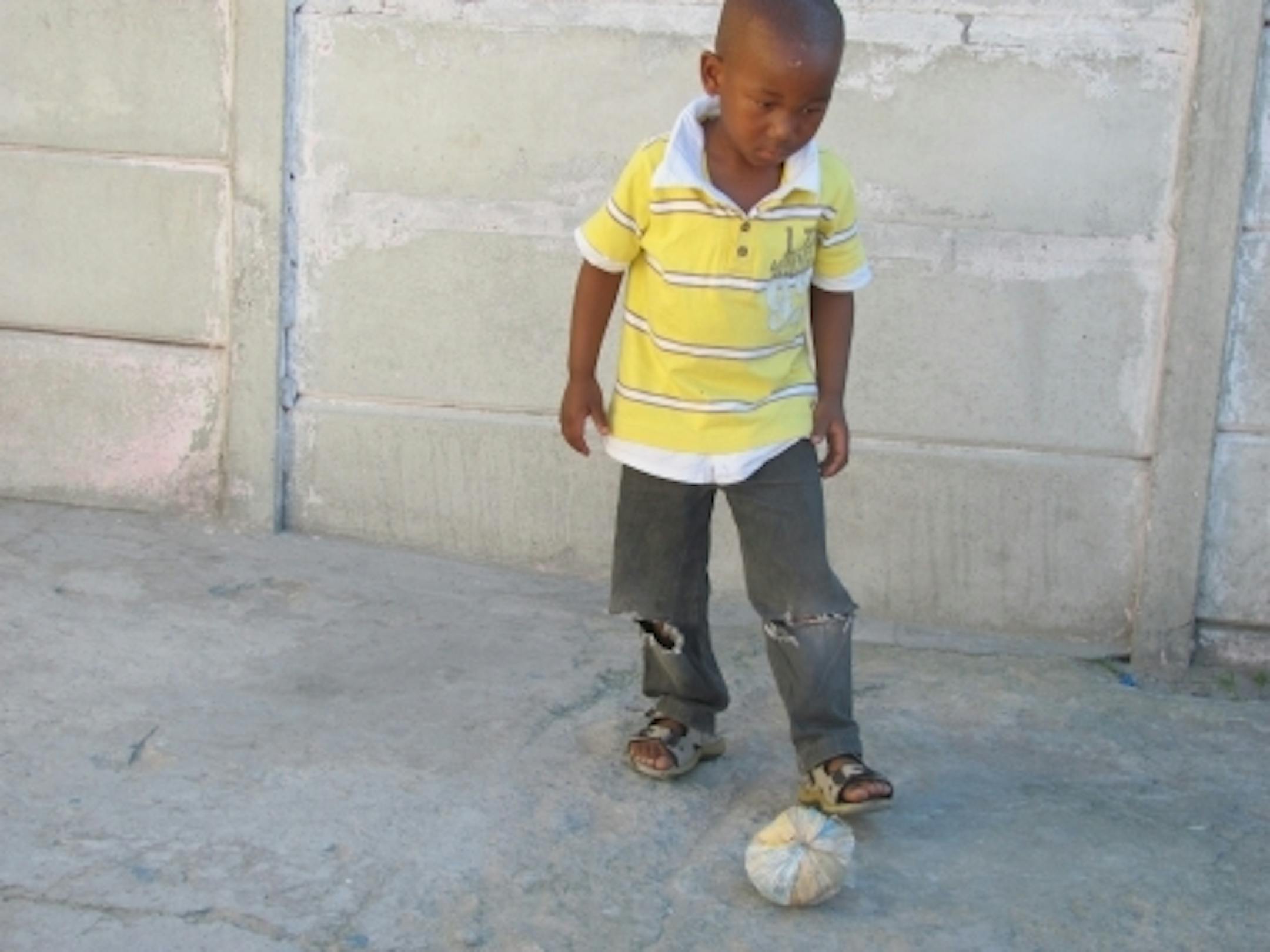 A township kid plays with his "soccer" ball.