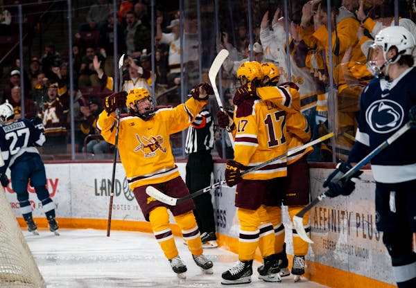 Gophers forward Connor Kurth (left) celebrates Aaron Huglen’s (7) first of two goals in the second period Saturday against Penn State.