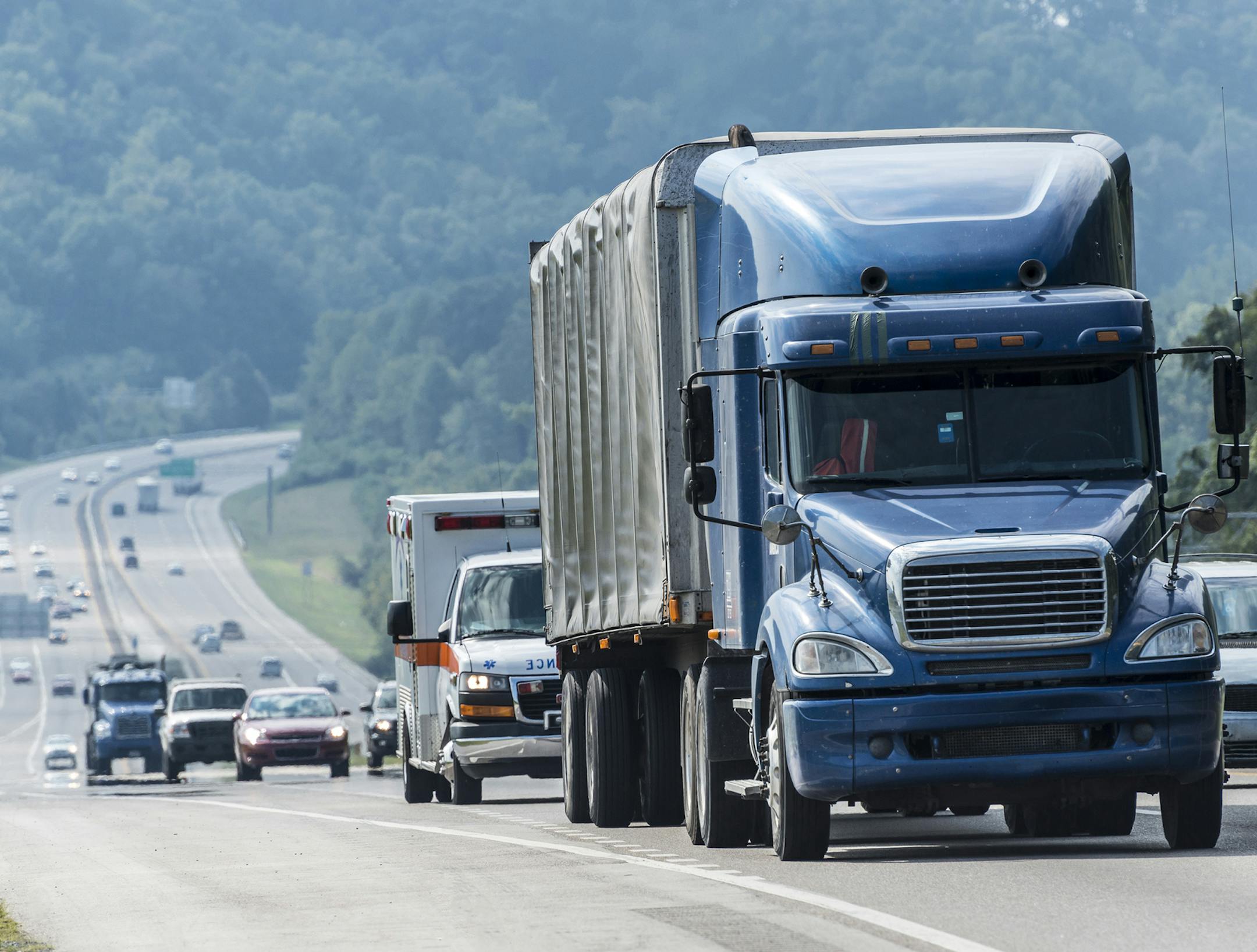 A blue semi leads a line of interstate traffic on a foggy morning.