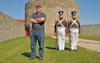 Matthew Cassady (left) stands near two men dressed in periodic soldier costumes at Fort Snelling in St. Paul.