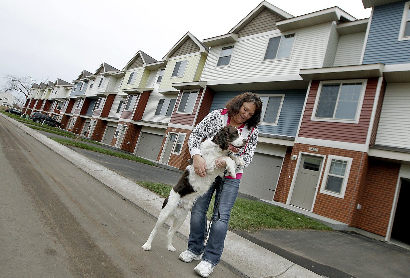 Kris Thuhl played with her dog "Max" outside the new home she just moved her family into, Thursday, November 14, 2013 in Ramsey, MN. UnitedHealth is investing $50 million in Minnesota to build affordable housing units. Their home, is in the Seasons Townhomes, a 50-unit complex in Ramsey that is part of a $100 million nationwide investment. (ELIZABETH FLORES/STAR TRIBUNE) ELIZABETH FLORES &#x2022; eflores@startribune.com