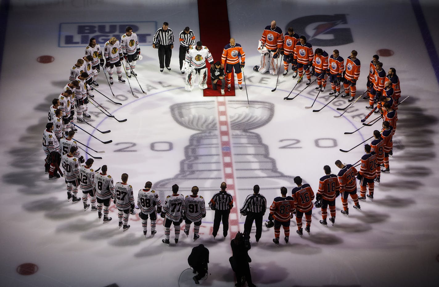 Minnesota Wild's Matt Dumba takes a knee during the national anthem flanked by Edmonton Oilers' Darnell Nurse, right, and Chicago Blackhawks' Malcolm Subban before an NHL hockey Stanley Cup playoff game in Edmonton, Alberta, Saturday, Aug. 1, 2020. (Jason Franson/The Canadian Press via AP)