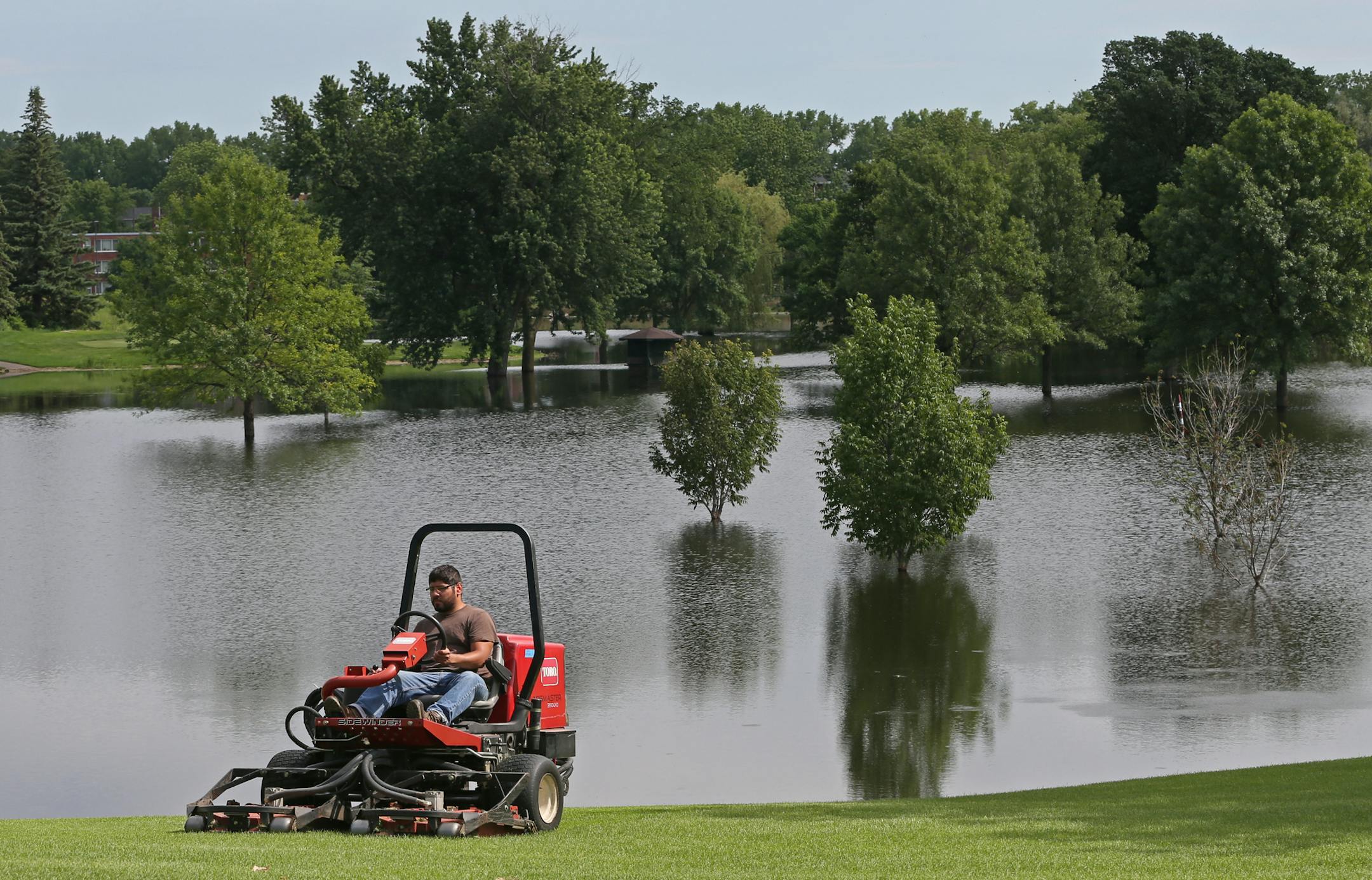 Joseph Schmerler, of the Meadowbrook Golf Course grounds crew, cut the lawn around the water-soaked course, which is closed until further notice.