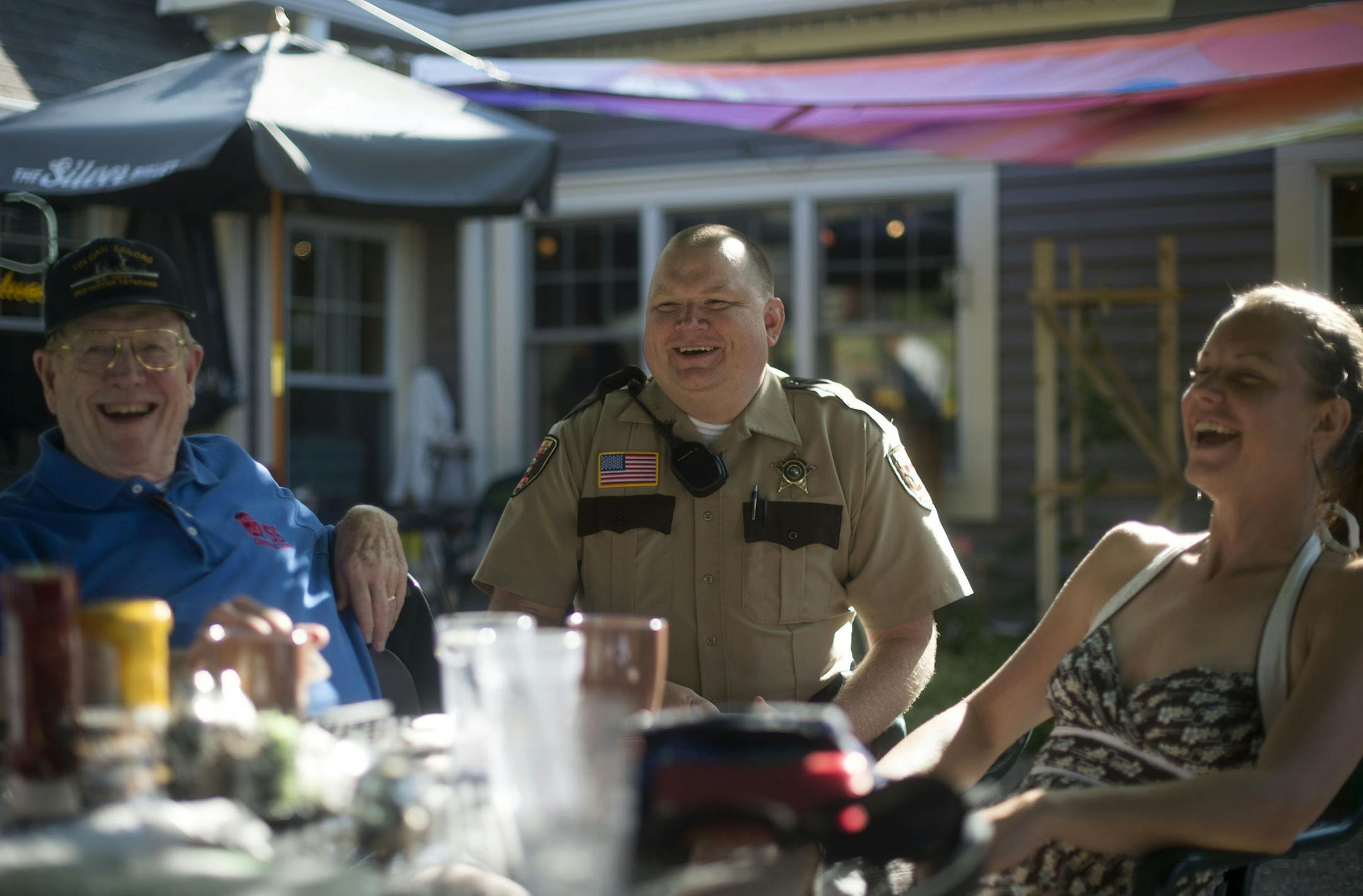 From left, Loring McAllister, of Afton, laughed with Deputy Sheriff Mark Rindfleisch and Carol Bjorklund, of Lake St. Croix Beach, as part of the Coffee With a Cop program in Afton, Minn., on Thursday July 23, 2015. The program intends for cops to meet and connect with law-abiding citizens of Washington County. ] RACHEL WOOLF · rachel.woolf@startribune.com