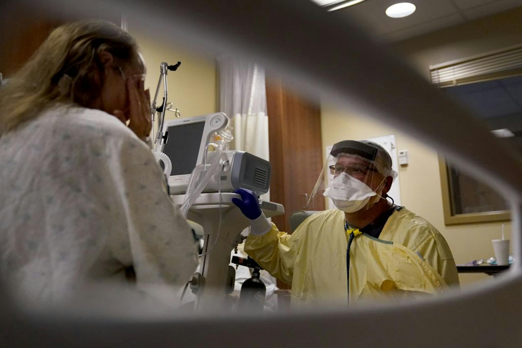 Dr. Shane Wilson kneels at the bedside of a patient suffering from COVID-19 inside Scotland County Hospital on Tuesday, Nov. 24, 2020, in Memphis, Mo. Wilson grew up in the area and personally knows many of the patients he is treating. "We have a really strong community. Very small. We're all friends and neighbors,'' Wilson said.