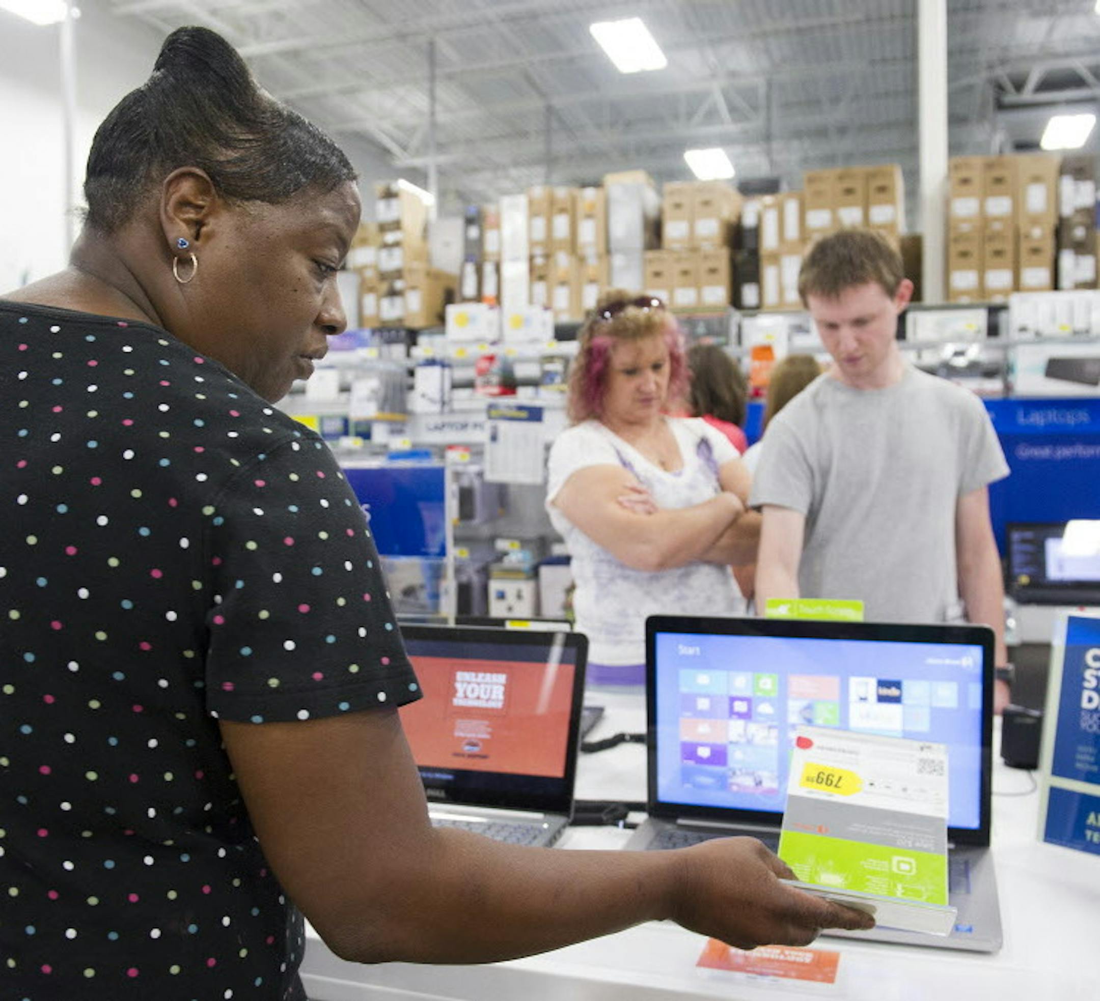Deborah Simmons looks at the price tag of a laptop computer as she shops with her 14-year-old son Carlos Simmons during a sales tax holiday sale at Best Buy on Friday, August 1, 2014 in Augusta, Ga. Officials said state and local sales taxes in most Georgia counties will be waived between Aug. 1 and 2. (AP Photo/The Augusta Chronicle, Sara Caldwell)