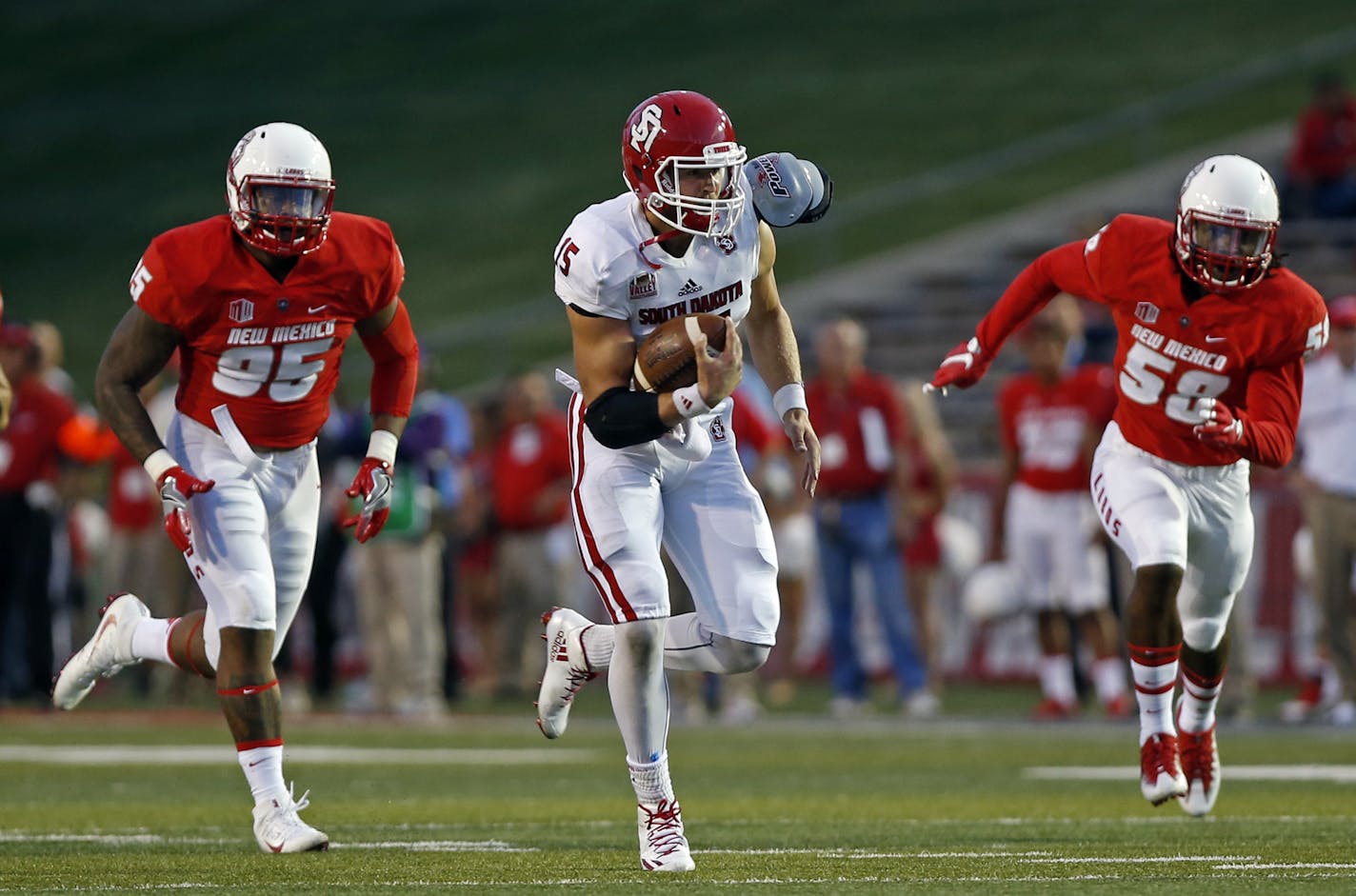 South Dakota quarterback Chris Streveler, center, sprints to the end zone for a touchdown ahead of New Mexico defensive lineman Garrett Hughes, left, and linebacker Maurice Daniels during the first half of an NCAA college football game in Albuquerque, N.M., Thursday, Sept. 1, 2016. (AP Photo/Andres Leighton) ORG XMIT: OTKAL114