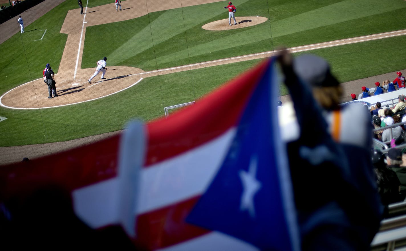 An exhibition baseball game between the Minnesota Twins and Puerto Rico takes place as a fan holds the flag of Puerto Rico from the stands, Wednesday, March 6, 2013, in Fort Myers, Fla. (AP Photo/David Goldman)