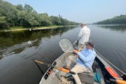 Fly angler John Butler hooks a smallmouth bass on a surface “popper’’ while his fishing partner, Ted Higman, leaves the oars of his drift boat p
