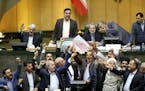 Iranian lawmakers burn two pieces of papers representing the U.S. flag and the nuclear deal as they chant slogans against the U.S. at the parliament i