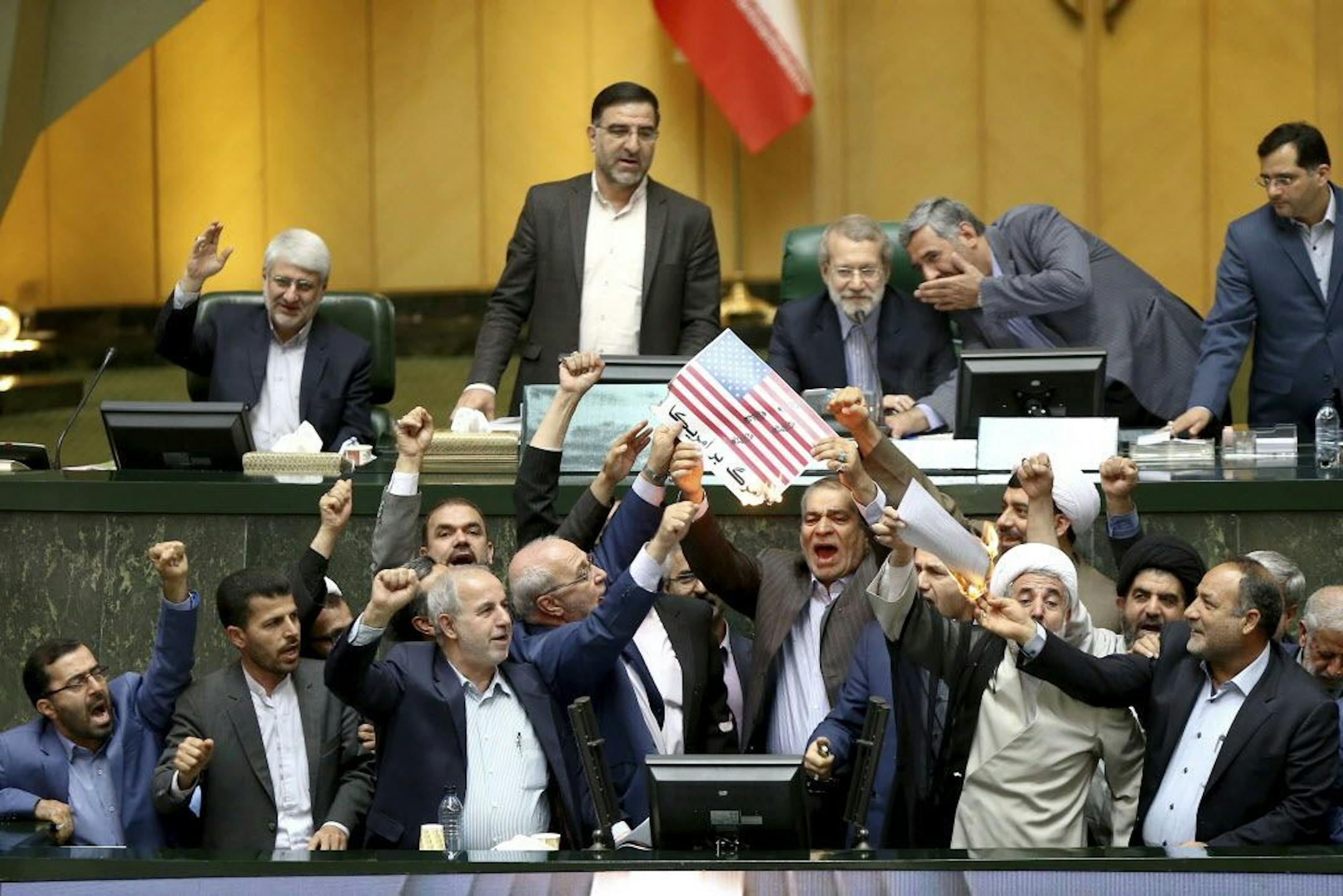 Iranian lawmakers burn two pieces of papers representing the U.S. flag and the nuclear deal as they chant slogans against the U.S. at the parliament in Tehran, Iran, Wednesday.