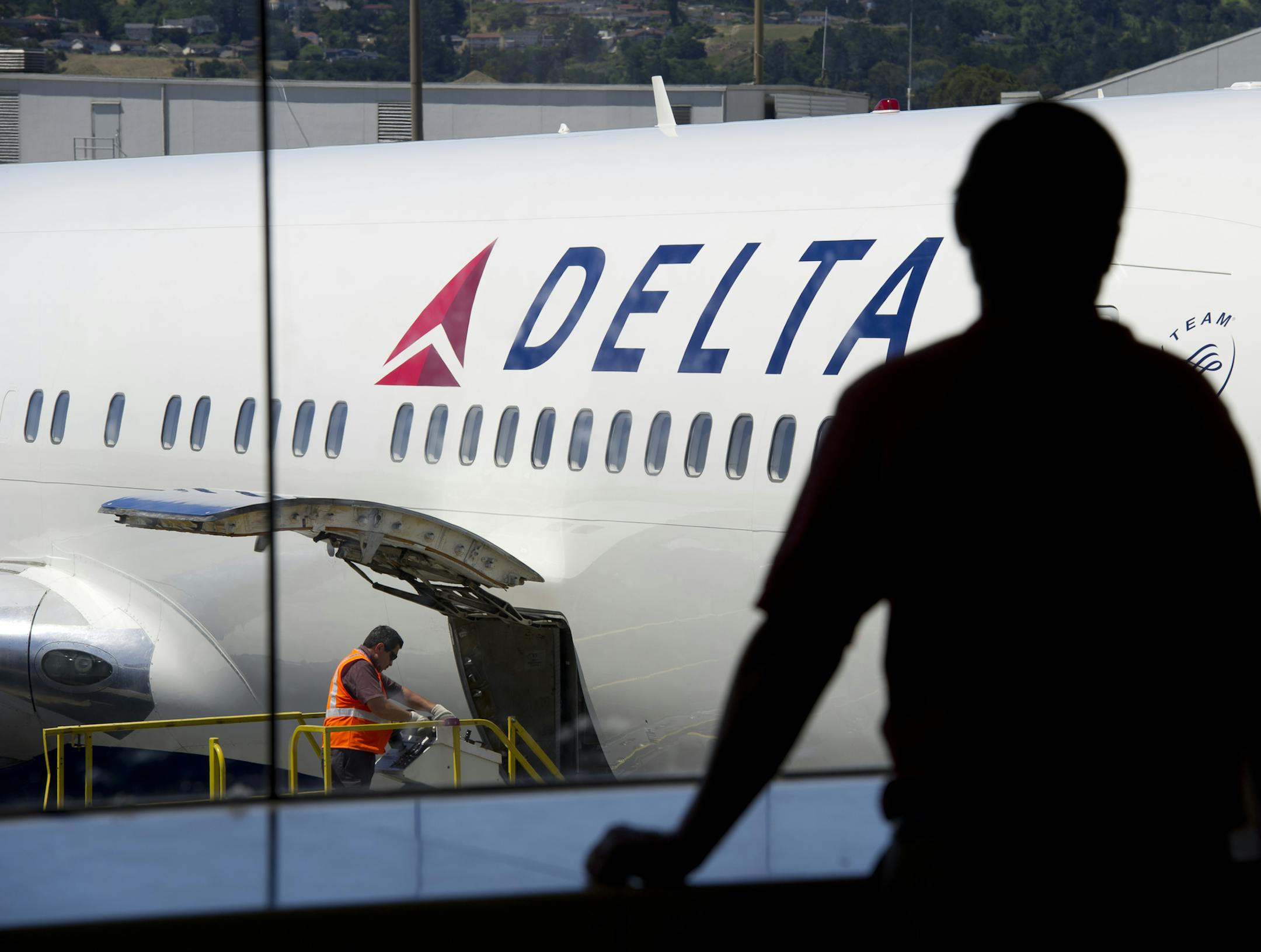 A passenger looks out towards a Delta Air Lines Inc. plane at San Francisco International Airport in San Francisco.