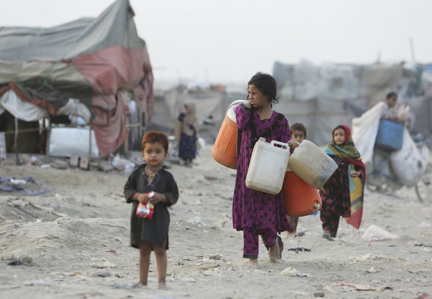 Afghan refugees who fled their homeland due to war and famine, are on their way to collect clean water in slums of Lahore, Pakistan, Wednesday, June 19, 2019. Pakistan will also observe the World Refugee Day tomorrow with other countries, launched by the UN Refugee Agency, and held every year on June 20th, aims to honors the courage of people who are forced to flee their homeland.