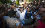 Haiti's former President Jean Bertrand Aristide, center, waves to the crowd after he urged supporters to vote for presidential candidate Maryse Narcis