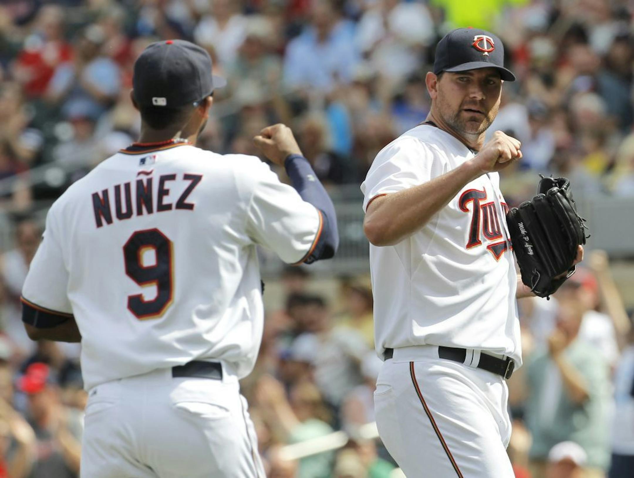 Minnesota Twins starting pitcher Mike Pelfrey, right, congratulates third baseman Eduardo Nunez (9) after Nunez caught a line to third by Milwaukee Brewers' Ryan Braun during the eighth inning of a baseball game in Minneapolis, Sunday, June 7, 2015. The Twins won 2-0.