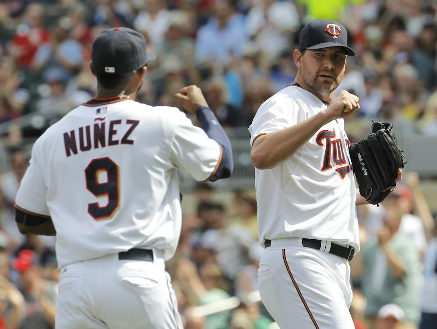 Minnesota Twins starting pitcher Mike Pelfrey, right, congratulates third baseman Eduardo Nunez (9) after Nunez caught a line to third by Milwaukee Brewers' Ryan Braun during the eighth inning of a baseball game in Minneapolis, Sunday, June 7, 2015. The Twins won 2-0.