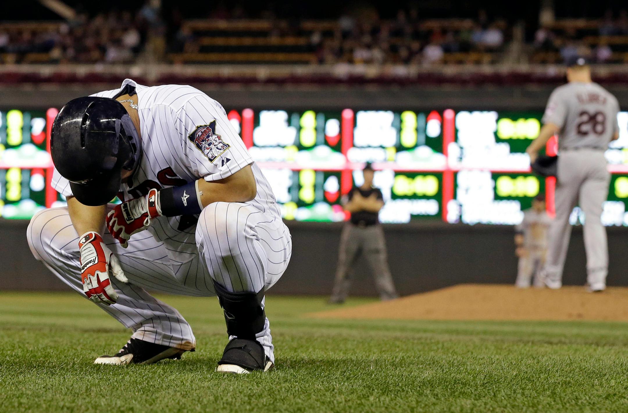 Minnesota Twins' Josmil Pinto gathers himself after he was hit by a pitch from Cleveland Indians' Corey Kluber, right, in the fourth inning of a baseball game on Friday, Sept. 27, 2013, in Minneapolis. Pinto left the game with a bruised right hand. (AP Photo/Jim Mone)