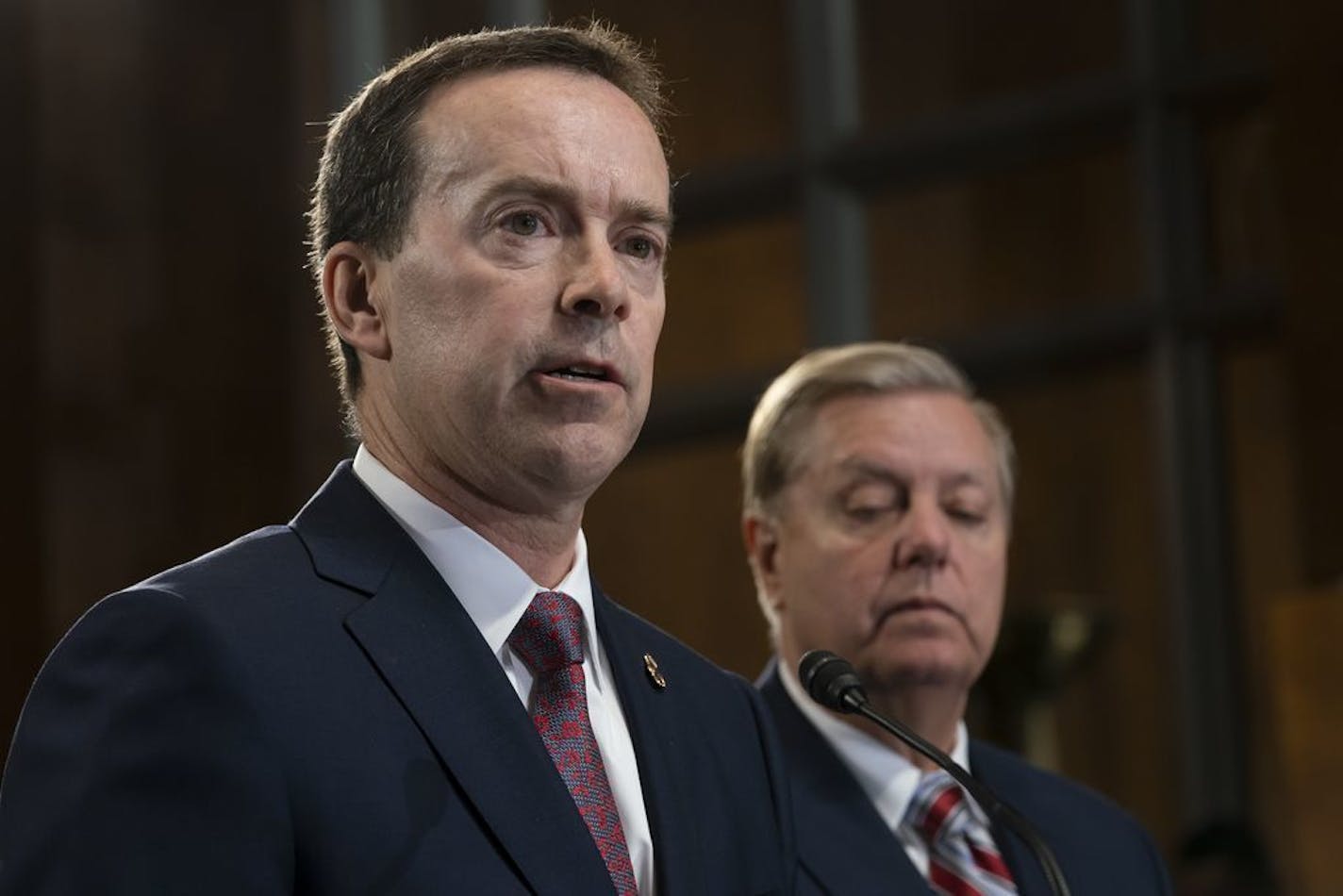 FILE - In this May 15, 2019, file photo, acting U.S. Customs and Border Protection Commissioner John Sanders, left, joins Senate Judiciary Committee Chairman Lindsey Graham, R-S.C., right, on Capitol Hill in Washington. Sanders says he's stepping down amid outrage over his agency's treatment of detained migrant children and said in a message to CBP employees Tuesday that he would resign on July 5.