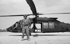 A Marine stands in front of a helicopter in Afghanistan.