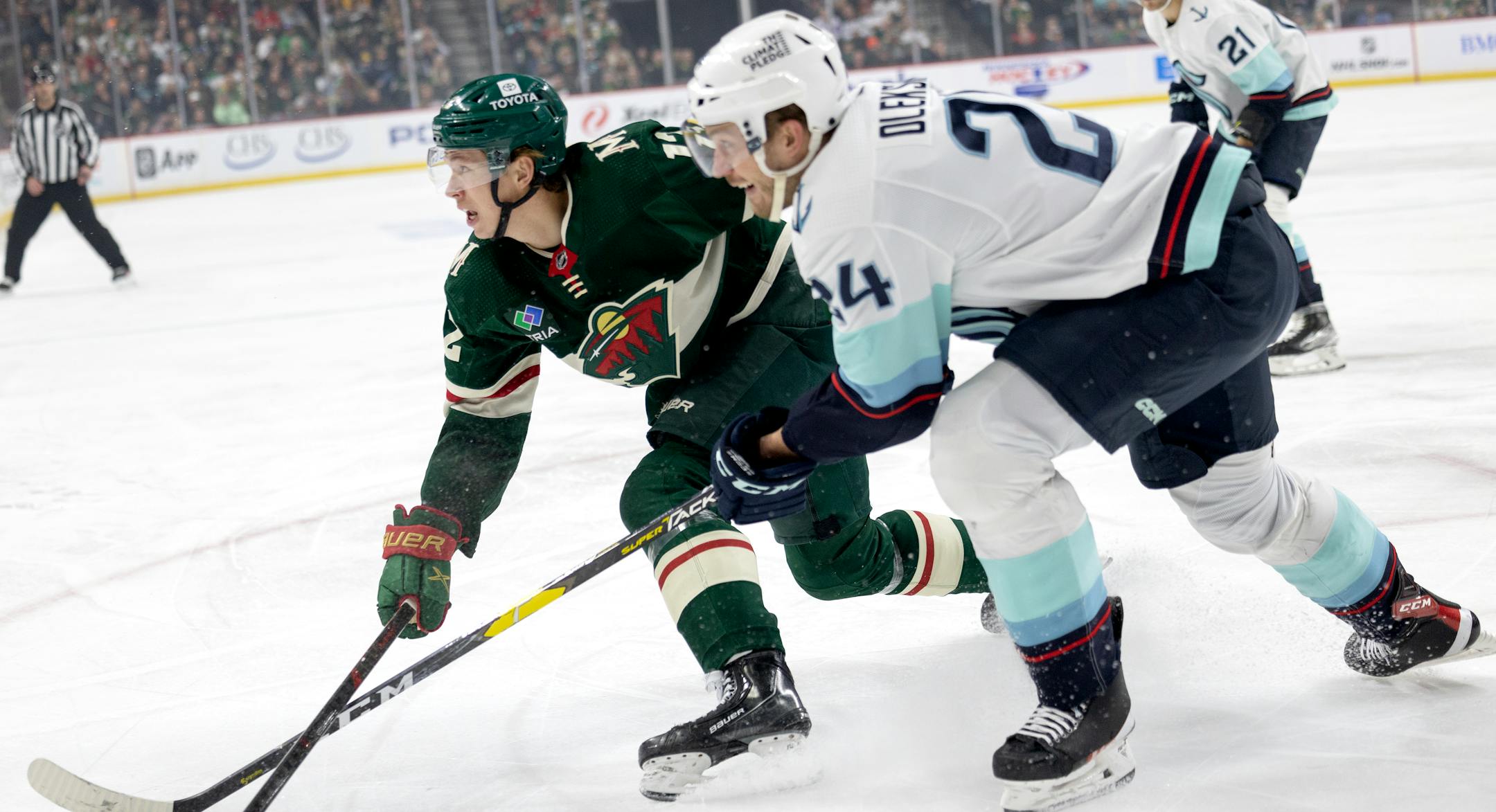 Matt Boldy (12) of the Minnesota Wild and Jamie Oleksiak (24) of the Seattle Kraken chase the puck in the first period.