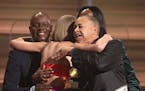 Philip Bailey, from left, Verdine White, obscured, and Ralph Johnson of Earth Wind & Fire present Taylor Swift the award for album of the year for �