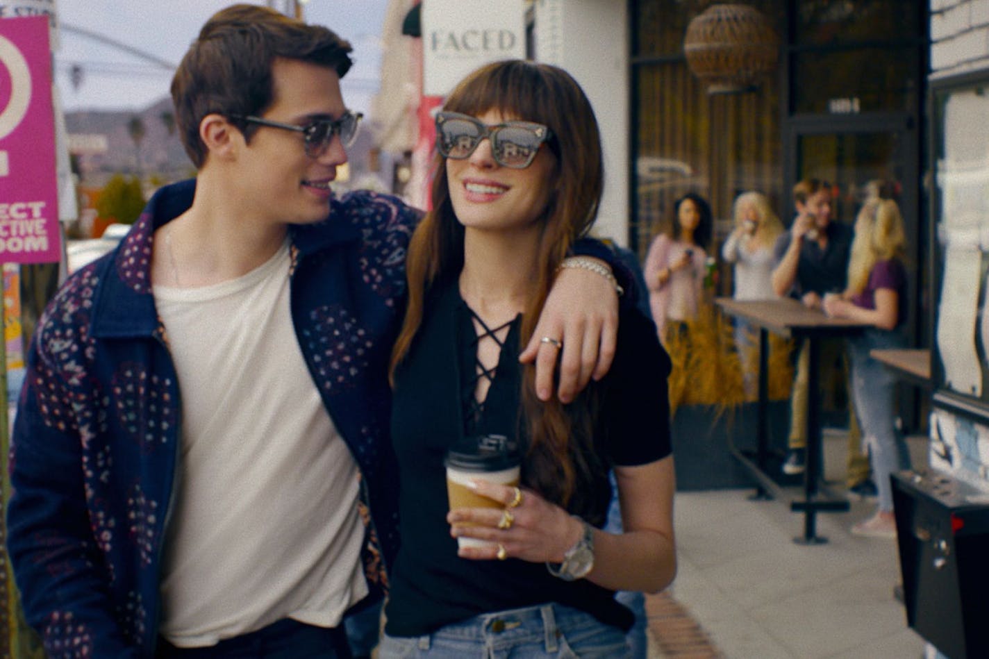 photo of two people strolling past a coffee shop, smiling